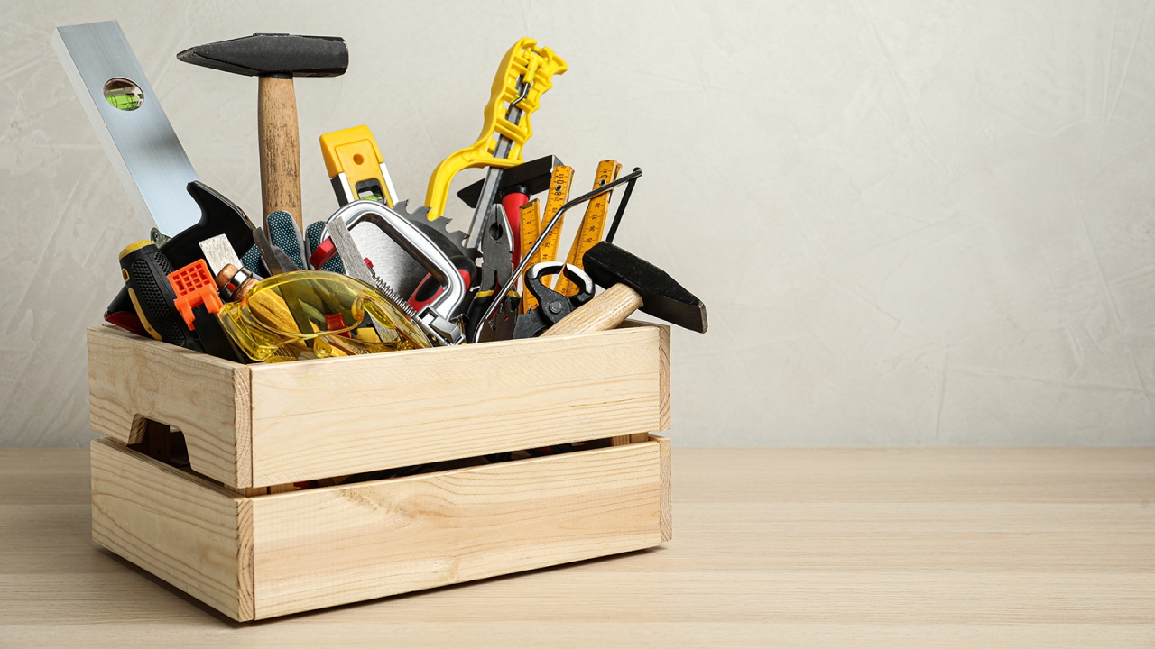 Kiste mit unterschiedlichen Schreinerwerkzeugen auf einem Holztisch.
